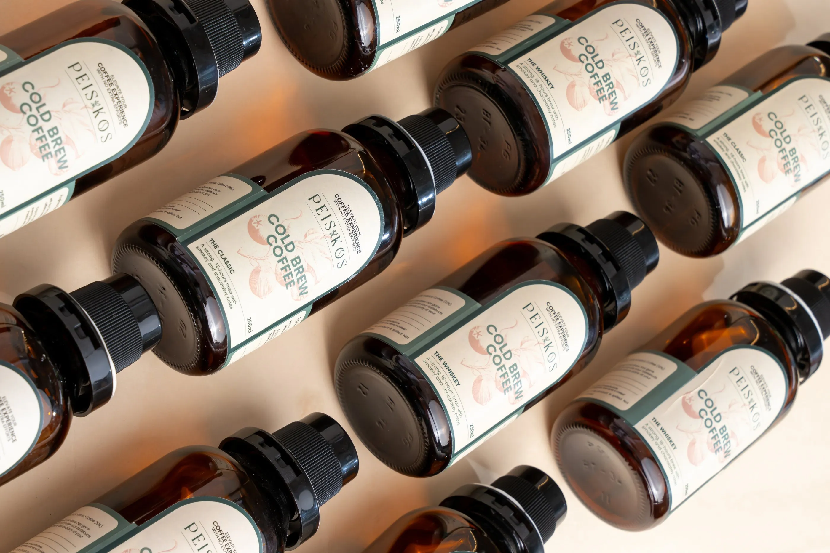 Rows of amber cold brew coffee bottles with cream labels on a beige backdrop